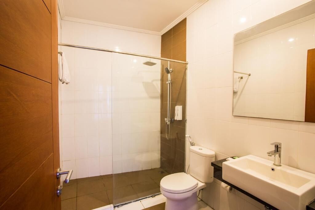 A modern bathroom with a glass-enclosed shower, a white toilet, and a sink with a mirror above it.