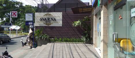 The exterior of the Svarna Hotel with a prominent sign, a tiled entrance, and a parked motorcycle.