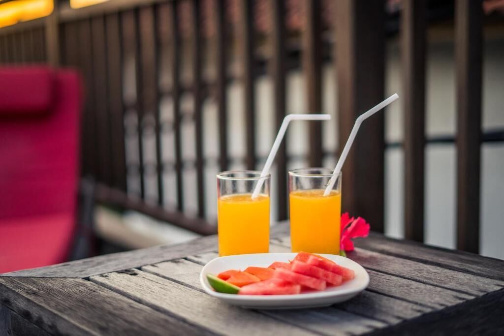 Ein Holztisch mit zwei Gläsern Orangensaft und einer Platte Wassermelonenscheiben.