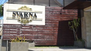 A hotel sign with the name 'SVARNA HOTEL' and a modern building facade with wooden panels and a sloped roof. - Svarna Hotel Sanur (Denpasar)