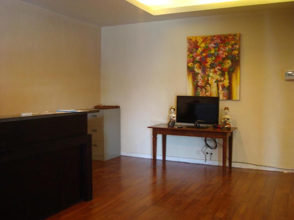 A room with a wooden desk, a television, and a painting on the wall.