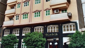 Un edificio de varios pisos con balcones, una entrada a nivel de calle con escalones y un letrero sobre la puerta.
