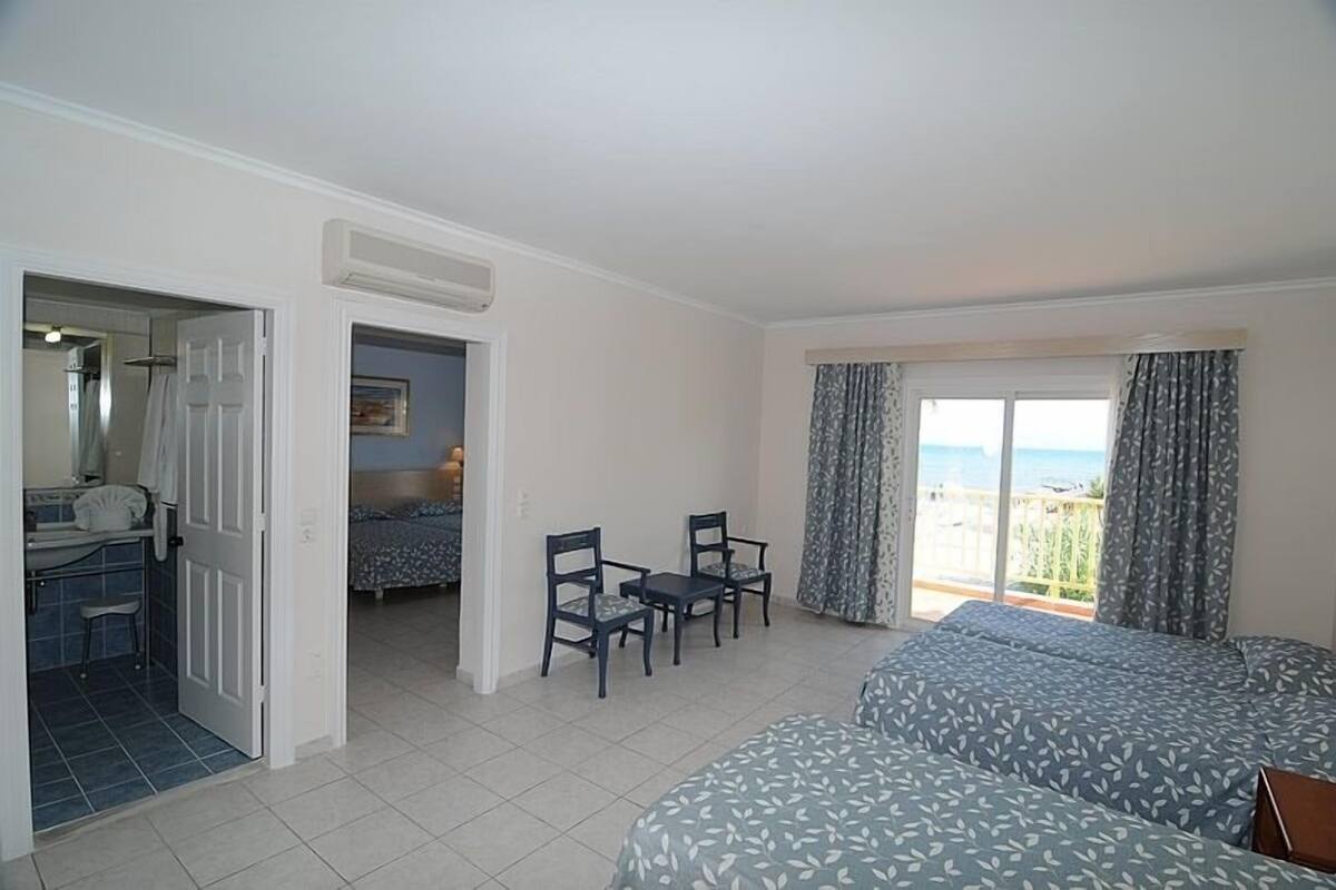 A hotel room with a balcony, a bed, a desk with a chair, and a bathroom.