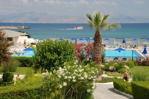 A resort with a pool, umbrellas, and a view of the sea. - Mastichari Bay Hotel (Kos)