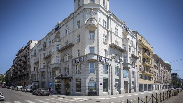 A corner building with multiple floors, featuring a prominent "JUMP INN" sign on the ground floor.