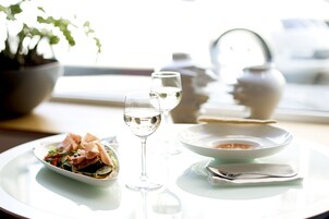 Ein Esstisch mit Salat, zwei Weingläsern, einer Suppenschüssel und einem Löffel.