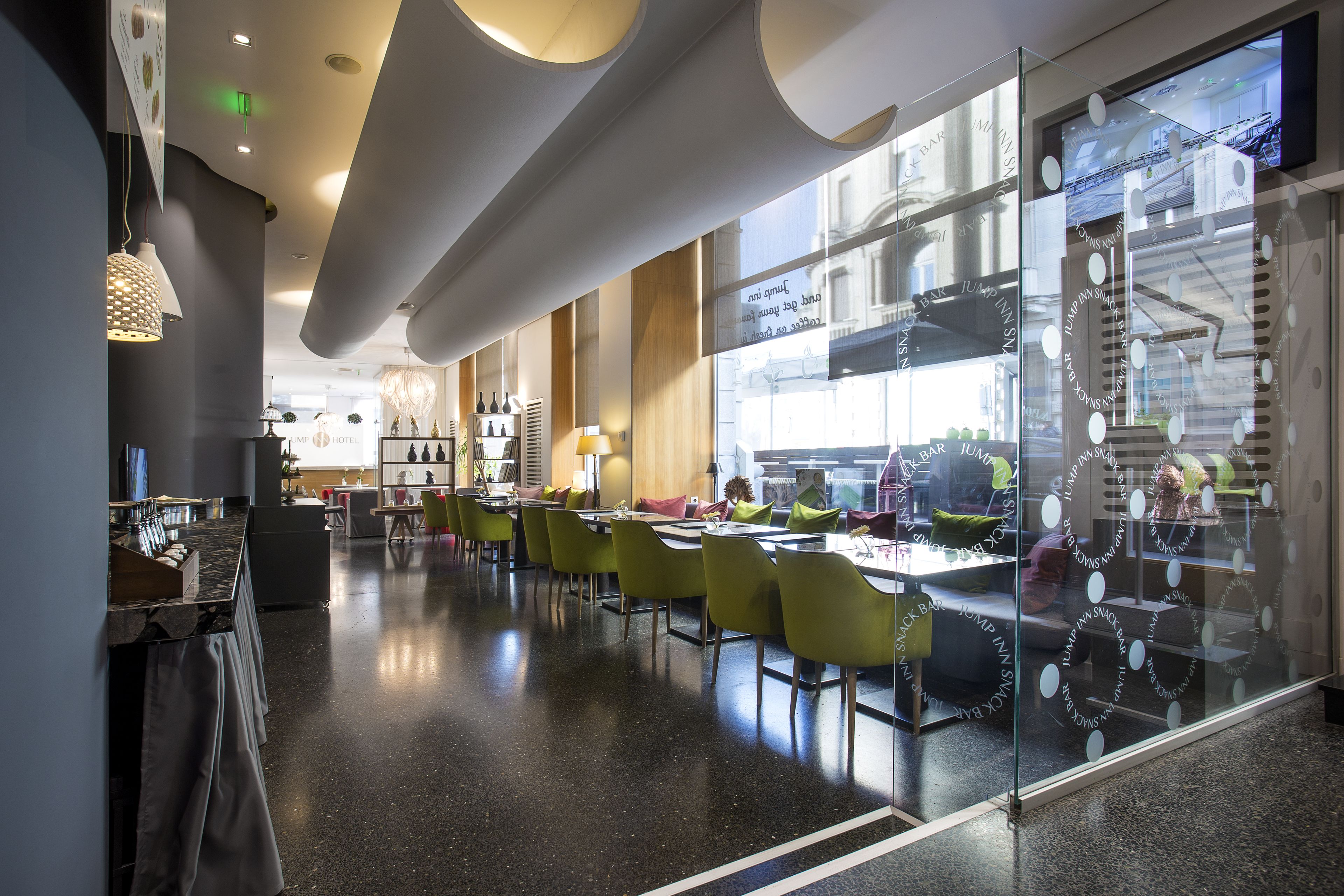 Un hall d’hôtel moderne, doté d’un aménagement spacieux, d’un bar et de grandes fenêtres offrant une vue sur la ville.