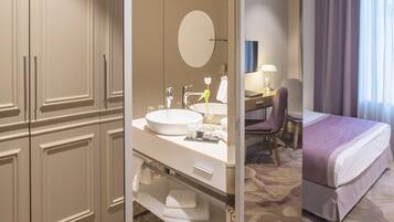A hotel room with a large mirror, a round mirror, a bed, a desk, and a chair.
