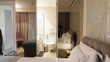 A hotel room with a large bed, a chair, a desk, and a bathroom visible through an open door.