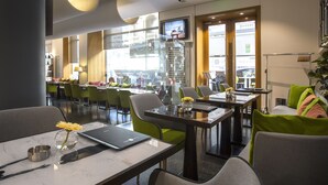 Un ristorante moderno con pareti divisorie in vetro, sedie verdi e grigie, e un portatile sul tavolo.
