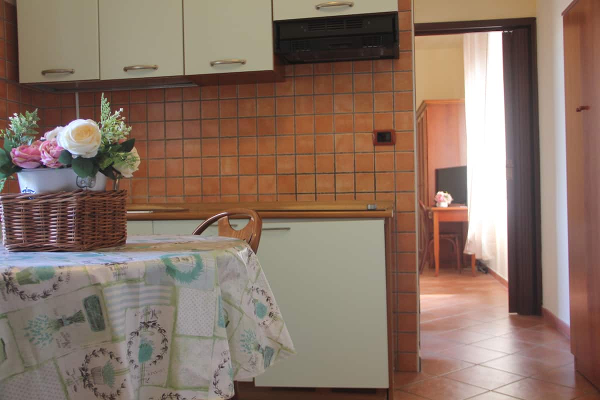 A kitchen with a tiled backsplash, a refrigerator, and a table with a floral tablecloth.