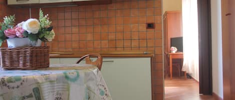 A kitchen with a tiled backsplash, a refrigerator, and a table with a floral tablecloth.