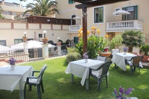 An outdoor patio area with tables and chairs, surrounded by potted plants and a small fountain. - Villino Gregoraci Relais (Santa Marinella)