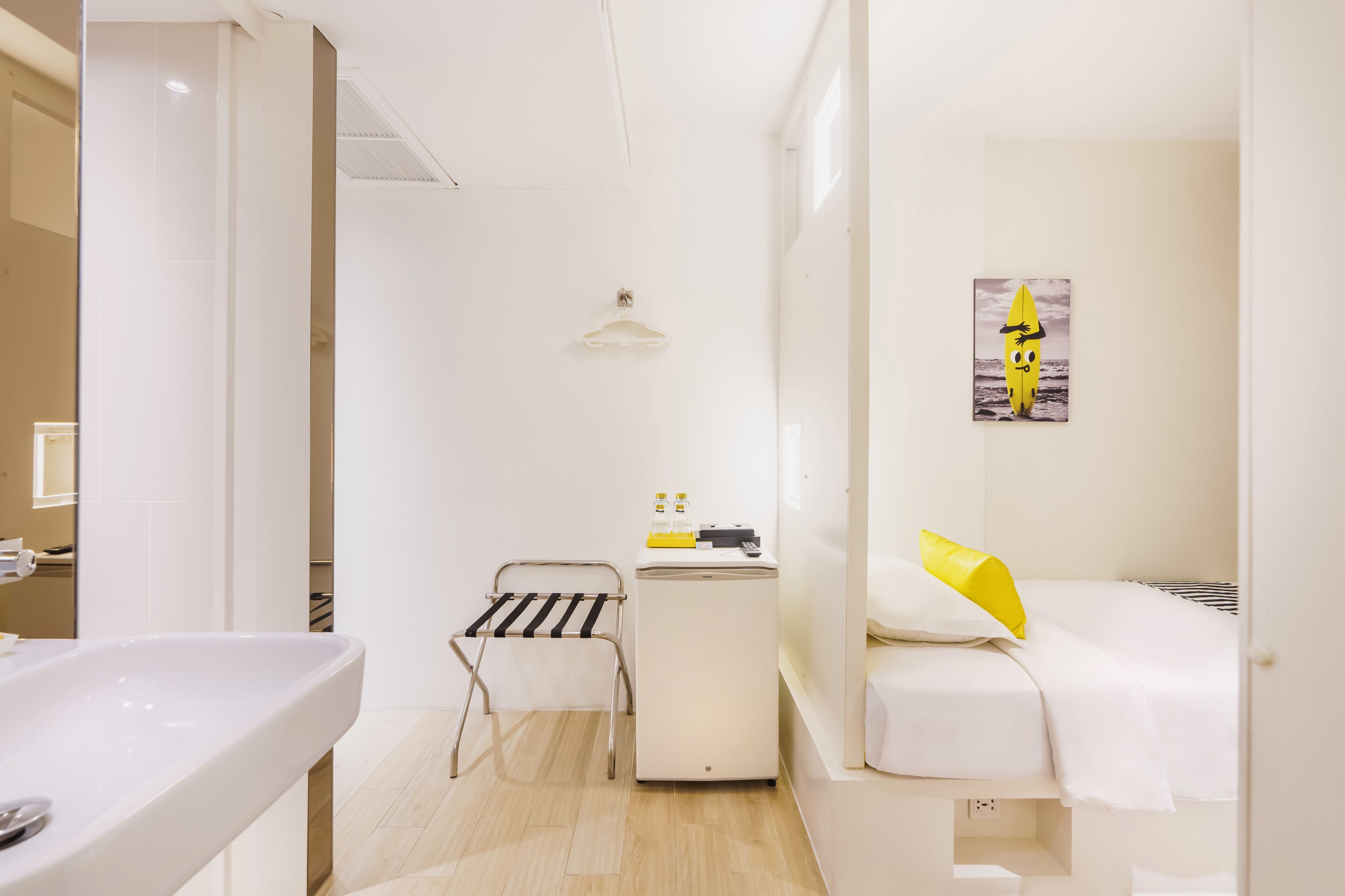 A small, clean room with a bed, a bedside table, a mirror, and a small white cabinet.