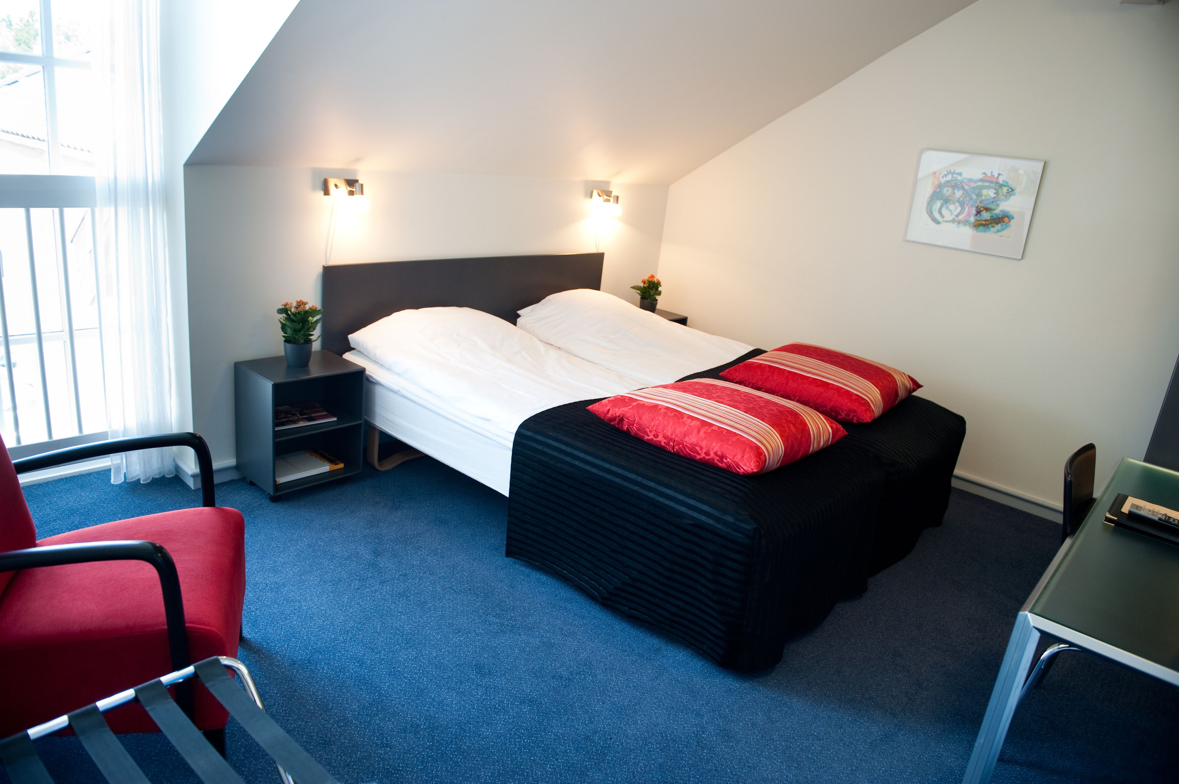 Une chambre à coucher avec un lit, des tables de chevet, une chaise, un bureau et une fenêtre.