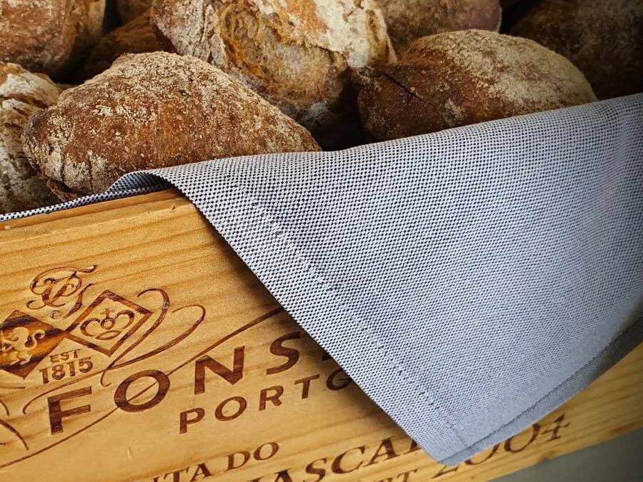 Una caja de madera con pan y un paño con texto.
