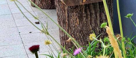 A wooden bench made from tree stumps, surrounded by greenery and flowers.