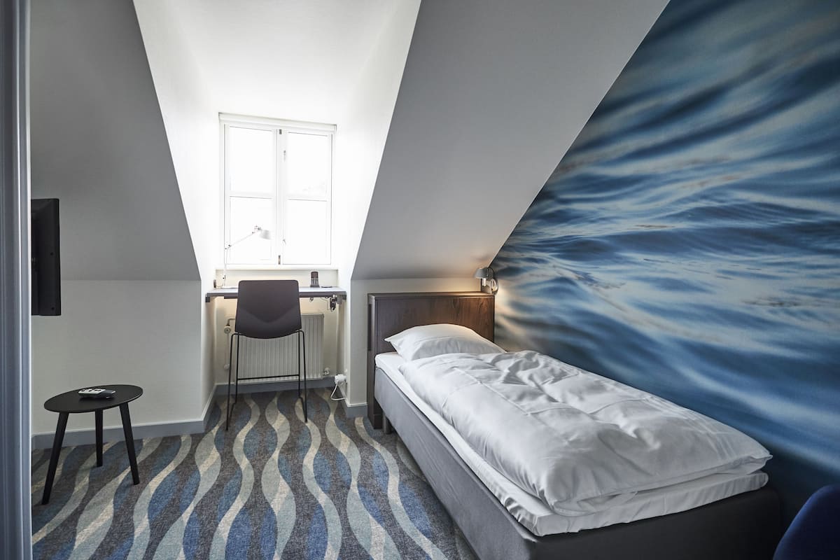 Une petite chambre moderne, équipée d’un lit, d’un bureau et d’une chaise.
