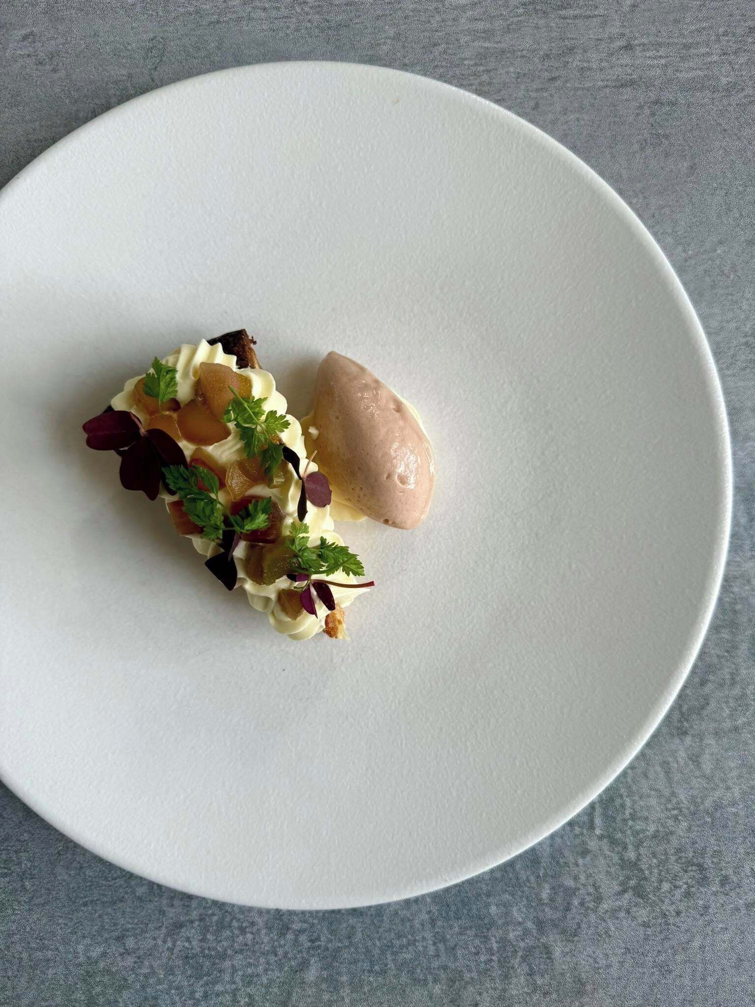 A white plate with a dessert on a textured grey surface.