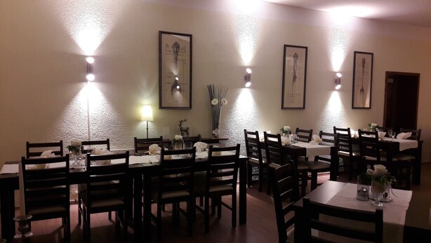 Un comedor con varias mesas y sillas, lámparas fijadas a la pared y obras de arte enmarcadas.