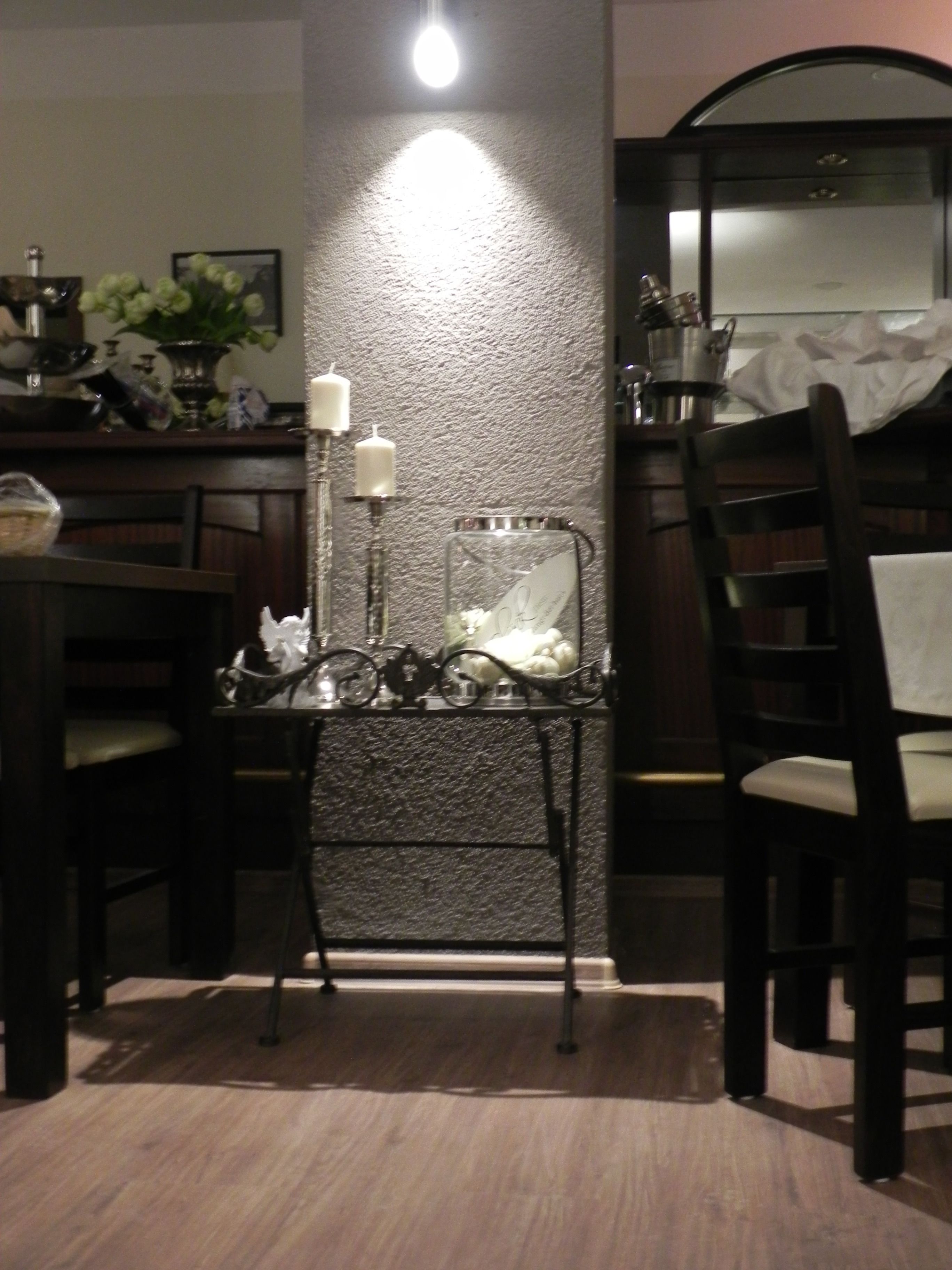 A dining area with a table and chairs, a wall-mounted light, and a decorative item with candles.