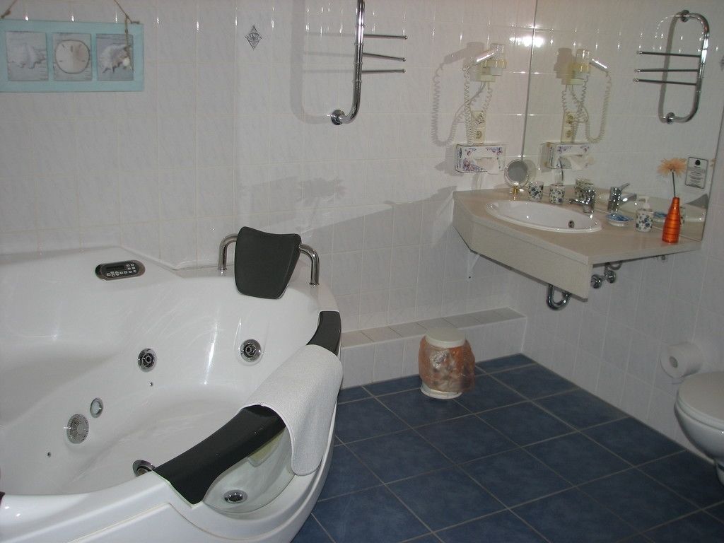 A bathroom with a bathtub, a sink, and a toilet. There are towels and toiletries on the counter.