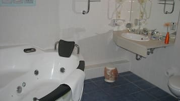 A bathroom with a bathtub, a sink, and a toilet. There are towels and toiletries on the counter.