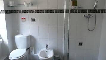 A bathroom with a toilet, bidet, and shower.