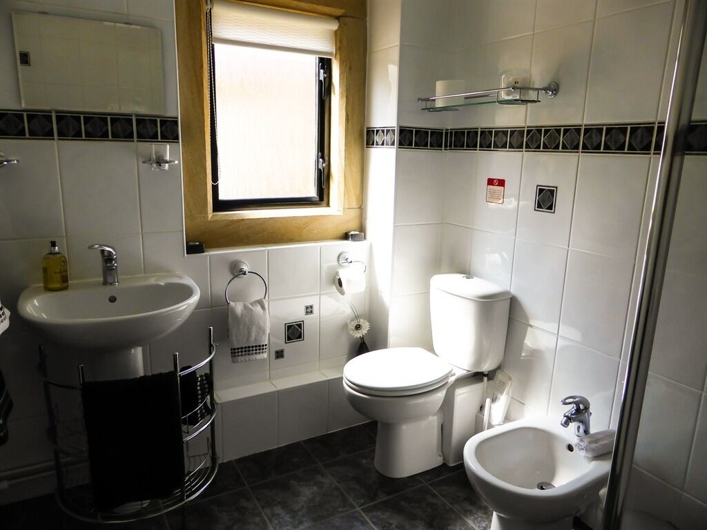 A bathroom with a sink, toilet, bidet, and a window.