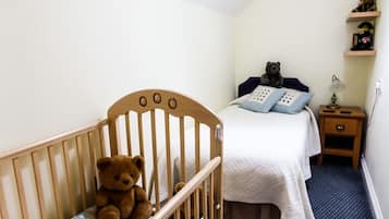 Cozy bedroom with a crib, single bed, and nightstand, perfect for a family stay.