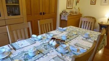 A dining area with a table set for four, wooden cabinets, and a small side table with a lamp.
