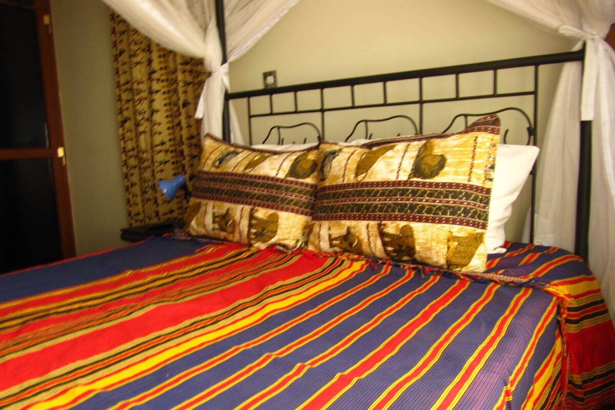 A bed with a striped bedspread and two patterned pillows.