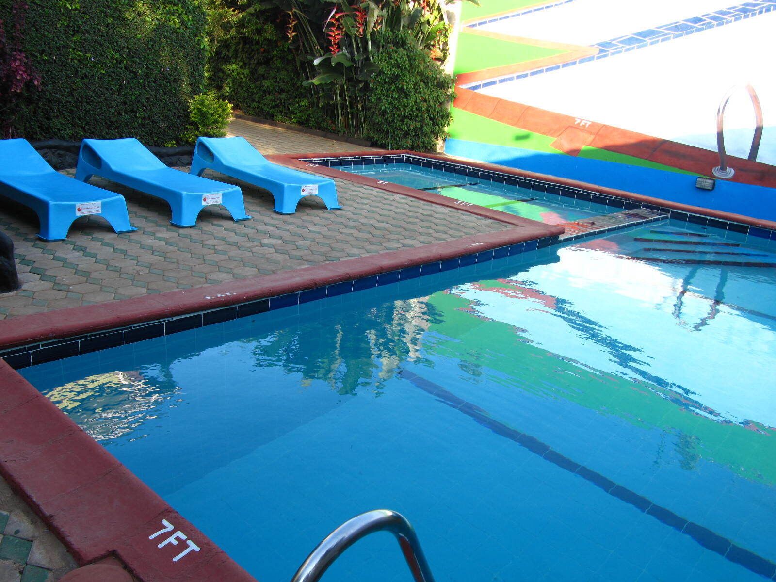 Una piscina al aire libre, sombrillas, sillones reclinables de piscina