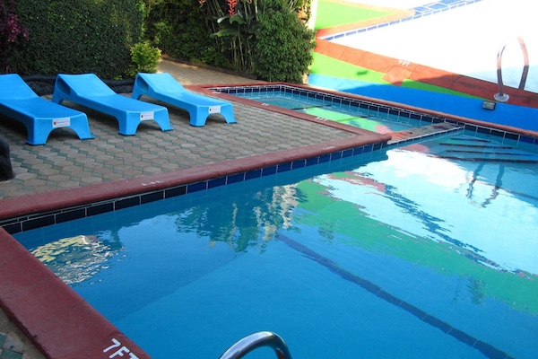 Una piscina al aire libre, sombrillas, sillones reclinables de piscina