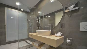 A modern bathroom with a glass-enclosed shower, a large mirror, and a beige vanity with a white sink.