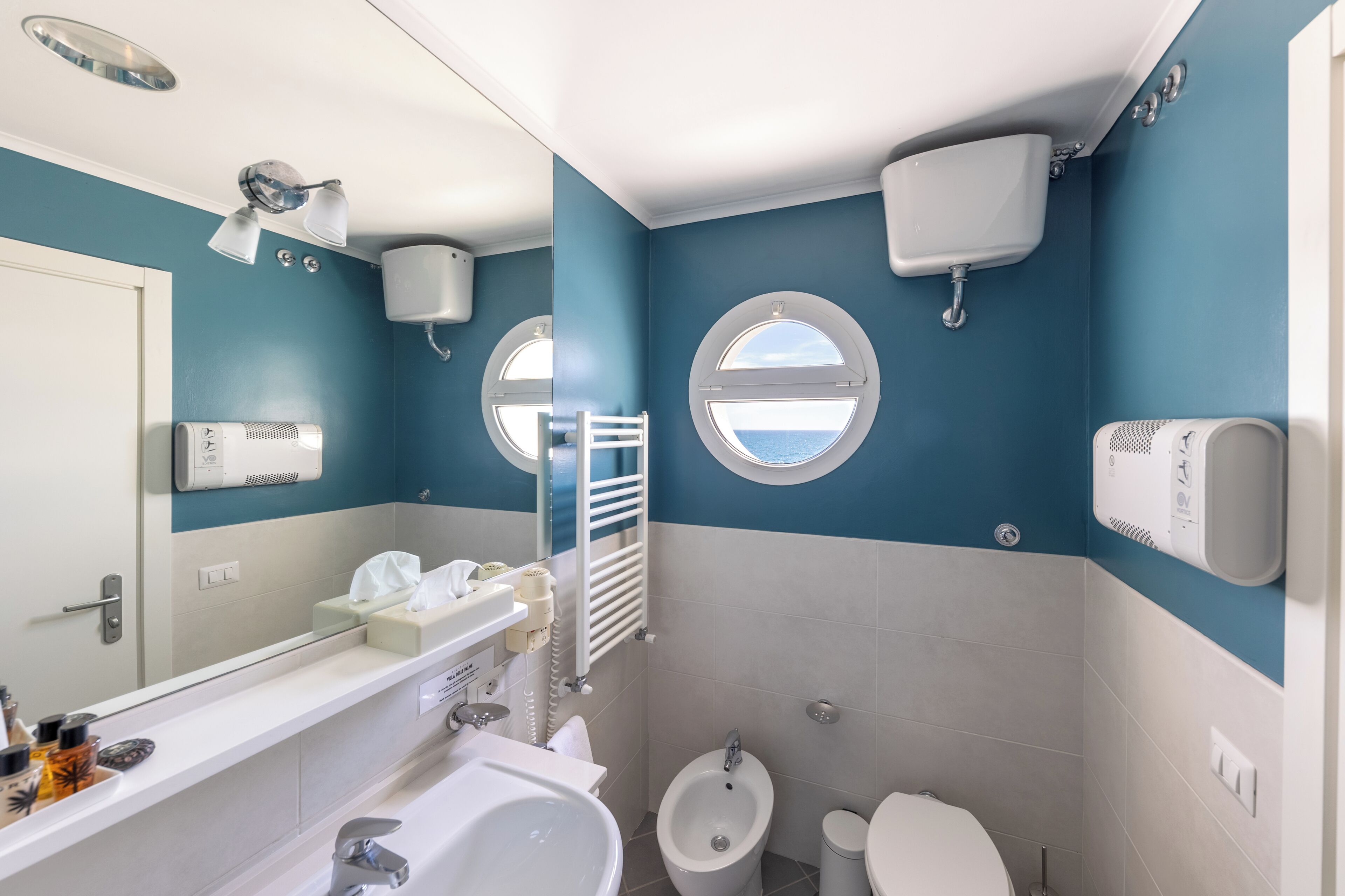 A bathroom with a bidet, toilet, sink, and mirror.