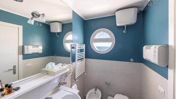 A bathroom with a bidet, toilet, sink, and mirror.