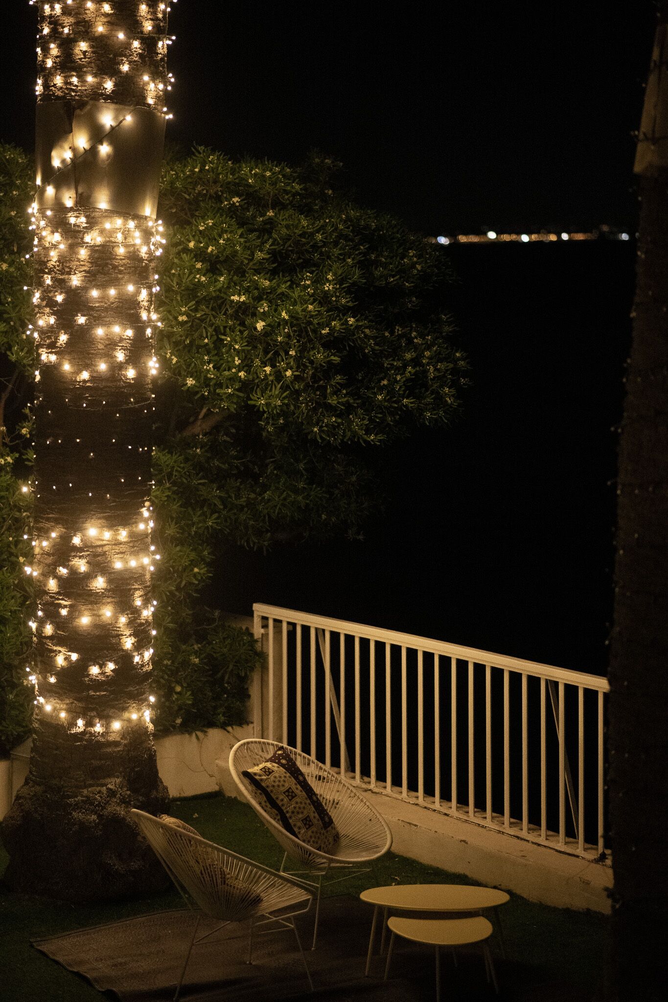 A balcony with a white railing, a white chair, and a small table.