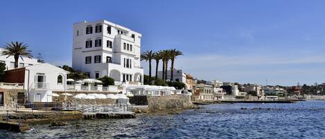 Een gebouw aan de kust met meerdere balkons en uitzicht op zee.