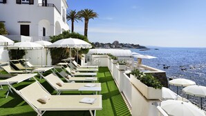 Une terrasse sur le toit, dotée de chaises longues, de parasols et offrant une vue sur la mer.
