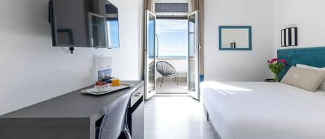 Ein Hotelzimmer mit Bett, Schreibtisch, Fernseher, Stuhl und einem Balkon mit Blick.