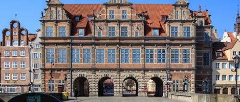 A historic building with multiple arches and a cobblestone street in front.