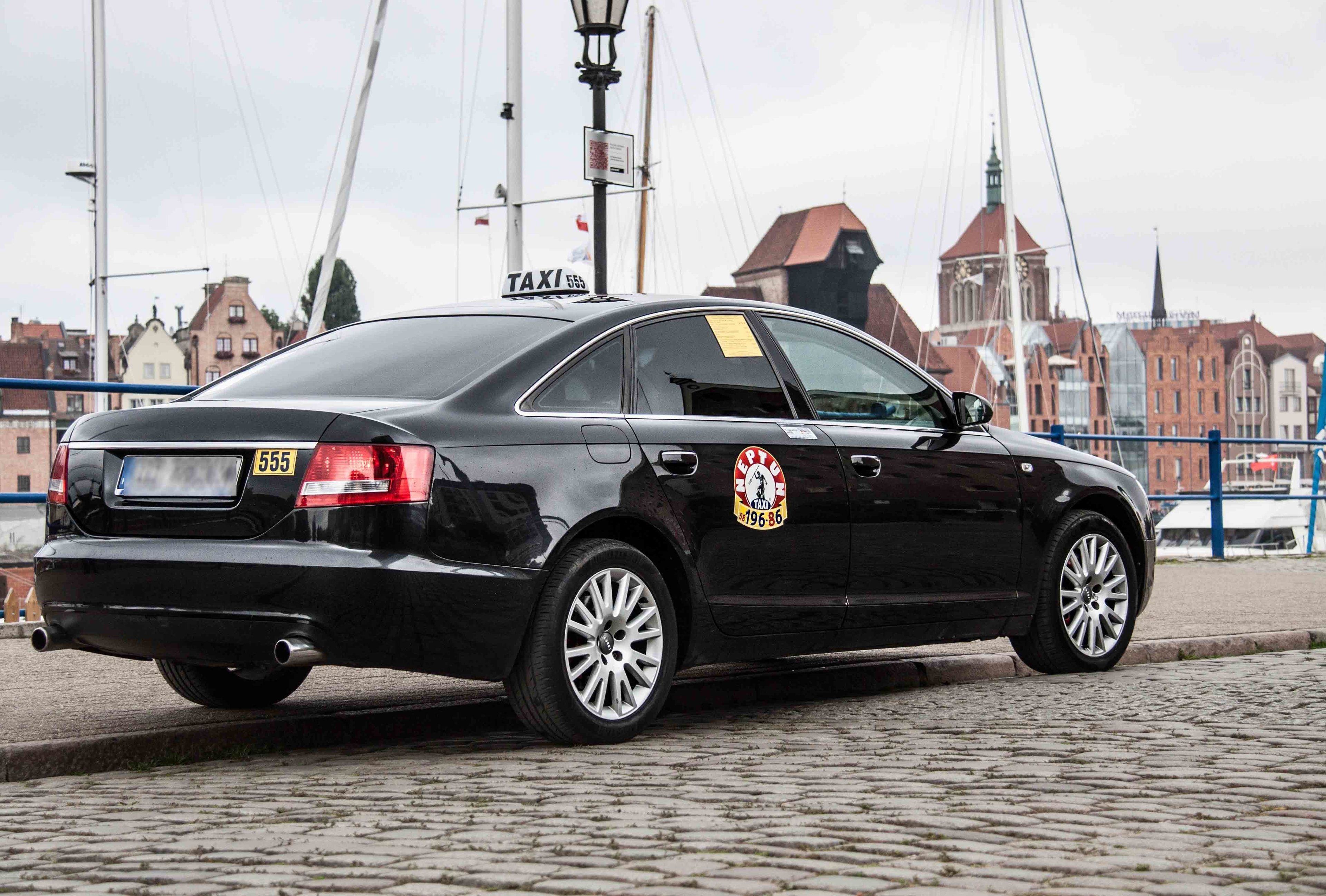 Un taxi negro con patente visible y un logotipo en la carrocería.