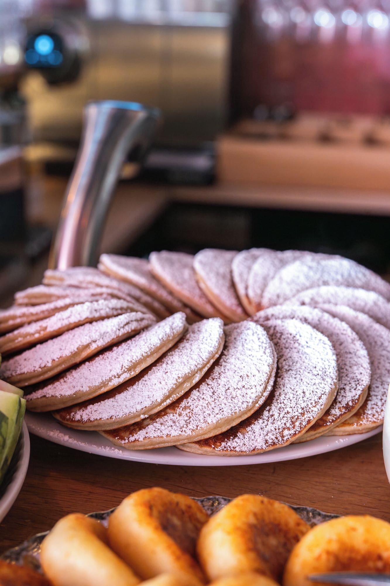 Une assiette de petits gâteaux ronds saupoudrés de sucre glace, disposés en cercle.