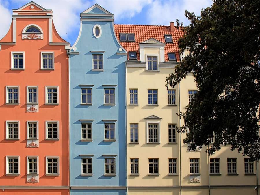 En rad med trevåningshus som har likadana fönster och en enhetlig arkitektonisk stil.