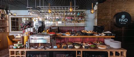 Zona de bar con enfriador de vinos, estanterías con botellas y una máquina de café.