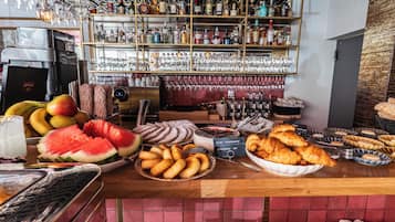 A bar area with a variety of food items, including bread, pastries, and fruits.