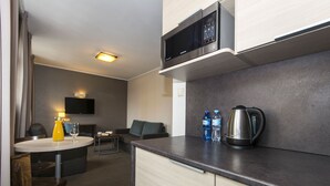 Habitación de hotel compacta con kitchenette, comedor y zona de estar.
