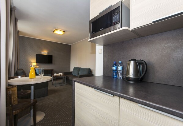 Une chambre d’hôtel compacte comprenant un coin cuisine, un espace repas et un coin salon.