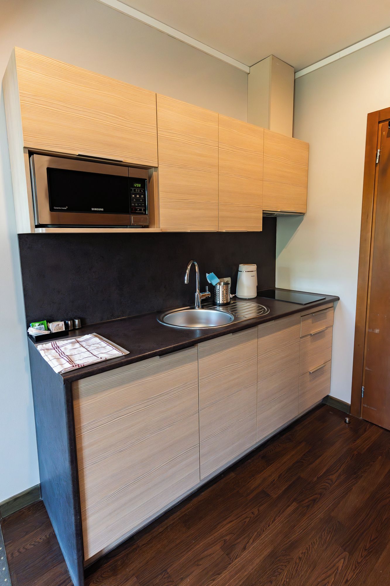 A compact kitchen with a microwave, sink, and a coffee maker.